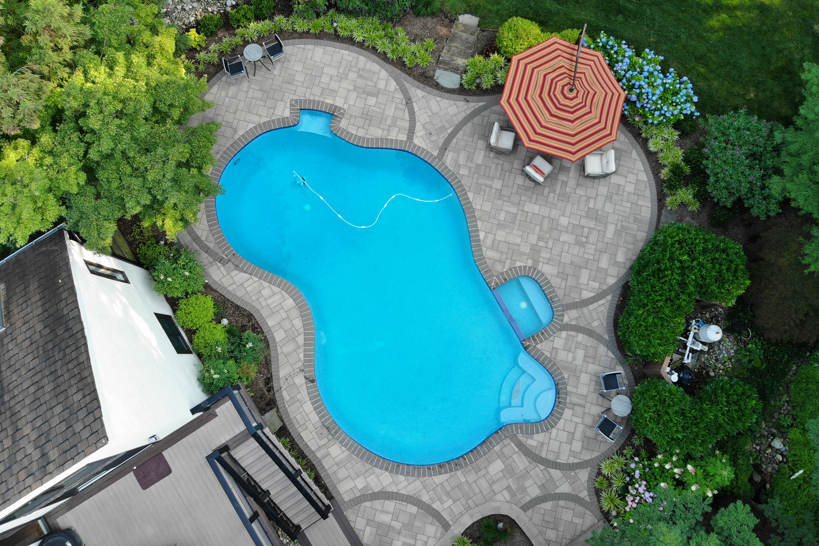 Overhead of pool with seating under umbrella in a home's backyard -Burkholder Landscape