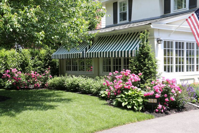 flowers and trees in front of a home with an awning - frony yard landscaping - Burkholder Landscape