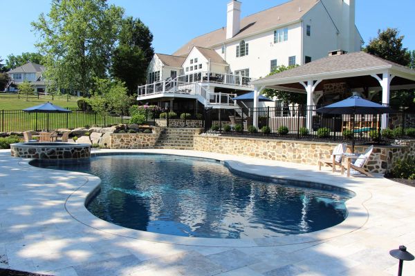 Rearview of a home with deck, pool, pool surround, pavilion and furniture | After Picture of ew Landscaping Project In Malvern | Burkholder Landscape