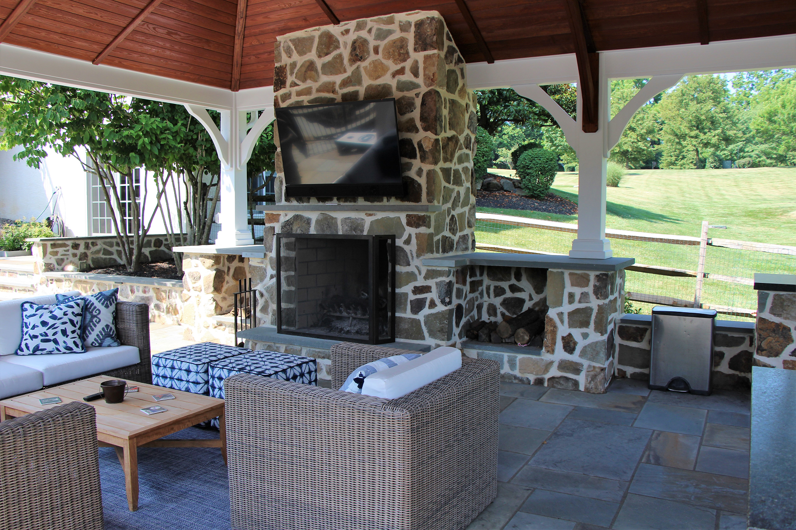 Pavilion with fireplace, TV, and seating area with wicker furniture -Investing in Landscape Design -Burkholder Landscape