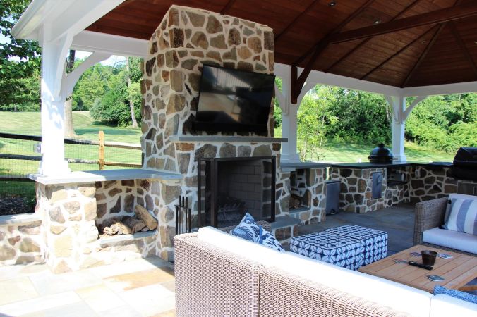 Stone outdoor fireplace set in a pavilion with seating | Fireplaces and Firepits Options by Burkholder Landscape