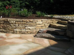 Natural stone retaining and seating wall with nearby steps | retaining walls | Burkholder Brothers