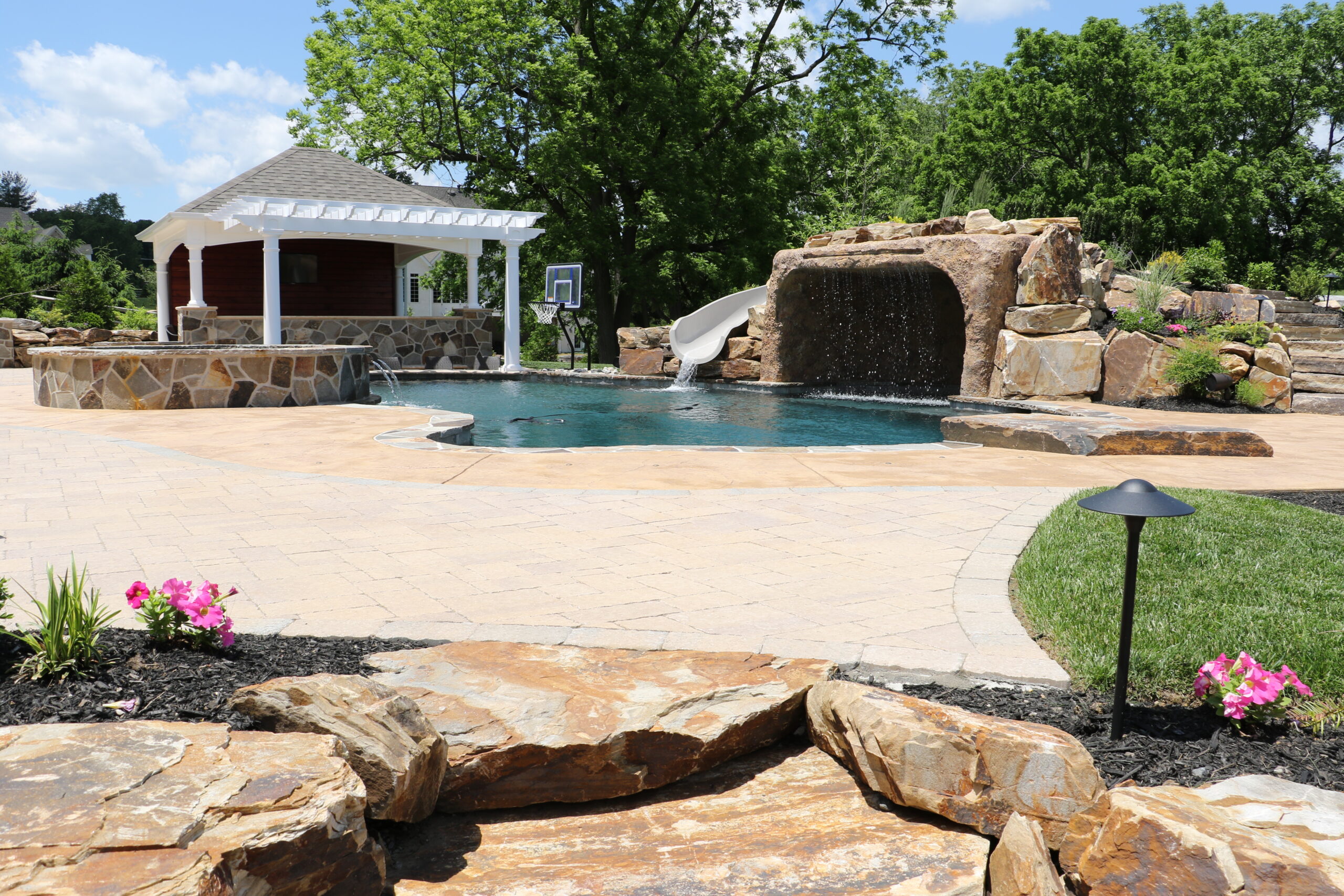 pool with slide feature and patio and pavilion - investing in landscape design - Burkholder Landscape