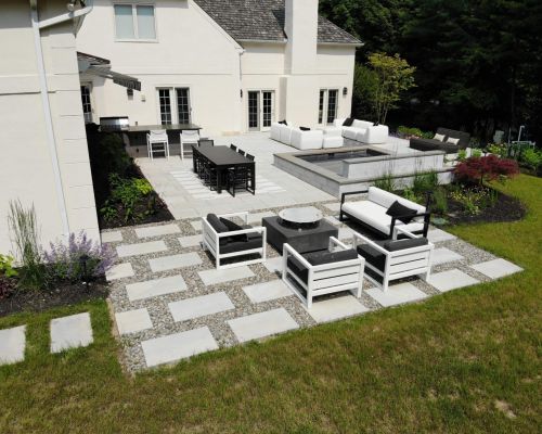Backyard Oasis from rear, outdoor furniture with black accessories, spa, outdoor kitchen and large Blu Grande pavers by Techo-Bloc - by Burkholder Landscape